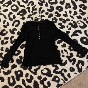 Black long sleeve Womens Shirt. Each sleeve has lace at the bottom.
